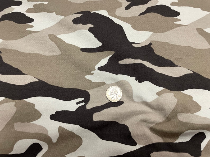 May include: Close-up of a camouflage fabric with a brown, white, and black pattern. A US quarter is placed on the fabric for scale.
