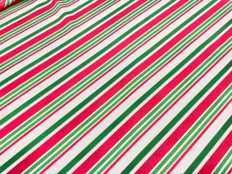 Peut inclure: Tissu ray&eacute; rouge et vert sur fond blanc. Les rayures sont diagonales et le tissu a une texture subtile.