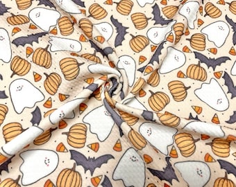 May include: A beige fabric with a Halloween-themed print featuring white ghosts, orange pumpkins, and black bats. The fabric has a waffle texture.