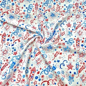 May include: White fabric with a repeating pattern of red and blue fireworks, stars, and spirals. The design features hand-drawn style illustrations of rockets, starbursts, and curly cues, creating a festive and celebratory theme.