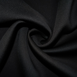 May include: Black fabric with a smooth, soft texture. The fabric is folded and draped in a swirling pattern.
