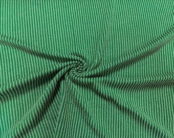 Puede incluir: Tela rayada verde y blanca con una superficie texturizada y acanalada. La tela está doblada y drapeada, mostrando la textura y el patrón.