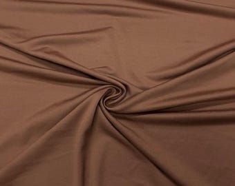 Könnte beinhalten: Nahaufnahme eines braunen Stoffes mit glatter, fließender Textur. Der Stoff ist drapiert und gerafft, wodurch weiche Falten und Schatten entstehen. Die Farbe ist ein sattes, warmes Braun, und das Material scheint leicht und flexibel zu sein.