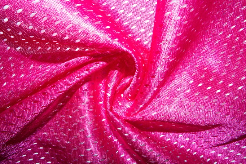 May include: Pink mesh fabric with a white dot pattern. The fabric is folded and twisted, creating a swirling effect.
