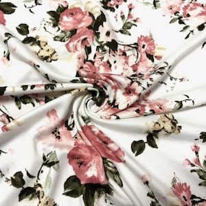 May include: White fabric with a pink and green floral print. The fabric is soft and has a subtle sheen.