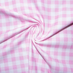 May include: Close-up of pink and white gingham fabric, with a swirled pattern in the centre. The fabric is soft and appears to be cotton or a similar material. The pattern is a classic checkered design.
