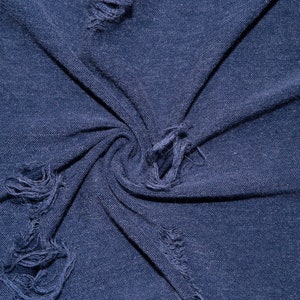 Könnte beinhalten: Nahaufnahme eines marineblauen Stoffes mit Distressed-Details. Der Stoff ist gewirbelt und zeigt mehrere ausgefranste Löcher im gesamten Material. Der Stoff hat ein strukturiertes Aussehen.