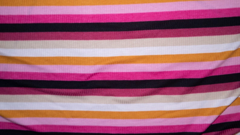 May include: Striped fabric with alternating bands of orange, pink, black, and beige.