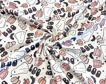 May include: White fabric with a repeating pattern of ghosts, pumpkins, bats, and the word "BOO" in black. The fabric has a ribbed texture.
