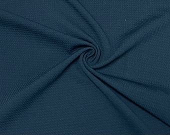 May include: A close-up of a dark blue waffle knit fabric. The fabric is soft and textured, with a subtle sheen.