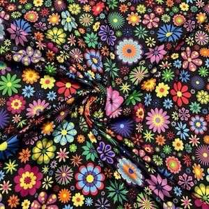 May include: A black fabric covered with a vibrant, colorful floral pattern. The design features a variety of stylized flowers in shades of pink, yellow, blue, green, and orange. The flowers are set against a dark background.