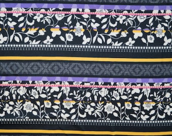 Peut inclure: Un tissu noir avec un motif répétitif de fleurs et de feuilles blanches. Le tissu a un design rayé avec des accents jaunes, violets et roses.