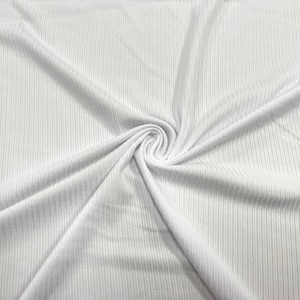 May include: White ribbed fabric with a soft, textured surface. The fabric is folded and draped, showing the texture and drape of the material.