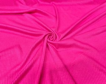 May include: A vibrant hot pink fabric featuring a distinct vertical ribbed texture. The material is gathered in the center, creating soft, flowing folds and shadows that highlight the consistent linear pattern across the entire surface of the textile.