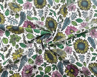 Puede incluir: Tela blanca con un patrón repetido de hojas verdes, flores rosas y girasoles amarillos. La tela está doblada en forma de espiral.