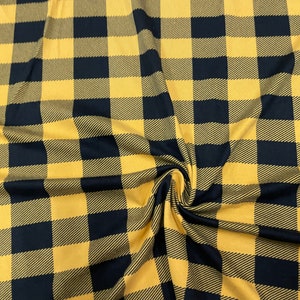 May include: Black and mustard yellow buffalo plaid fabric. The fabric has a woven texture.