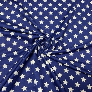 May include: A navy blue fabric with a repeating pattern of white five-pointed stars. The fabric is gathered and folded, creating a textured appearance. The stars are evenly spaced across the material.