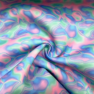 Puede incluir: Primer plano de una tela con un patrón arremolinado en colores pastel. La tela presenta tonos de rosa, azul y verde, con un brillo sutil. El diseño tiene una apariencia fluida y abstracta, que recuerda a la acuarela o el teñido anudado.