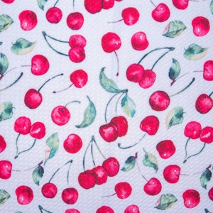 Puede incluir: Una tela con un patr&oacute;n repetido de cerezas rojas brillantes y hojas verdes sobre un fondo blanco. Las cerezas tienen un efecto de acuarela y el dise&ntilde;o est&aacute; uniformemente espaciado en la tela.