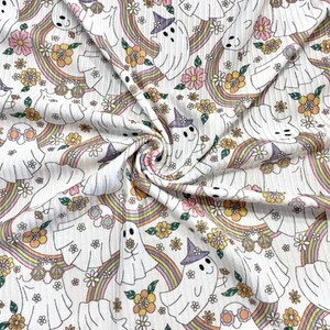 May include: White fabric with a repeating pattern of ghosts wearing sunglasses and witch hats, rainbows, and flowers.
