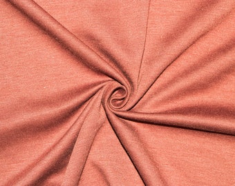 May include: Close-up of a rust-colored fabric with a subtle striped pattern. The fabric is folded and twisted, creating a swirling effect.