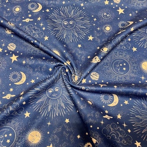 May include: Dark blue fabric with a celestial pattern featuring suns, moons, stars, planets, and clouds in a light beige color. The fabric is folded, showing the texture and design.