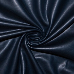 Könnte beinhalten: Nahaufnahme eines dunkelblauen Stoffes mit dezentem Glanz. Das Material ist drapiert und gewirbelt, wodurch weiche Falten und Schatten entstehen. Die Textur erscheint glatt, mit einem leicht sichtbaren Webmuster.