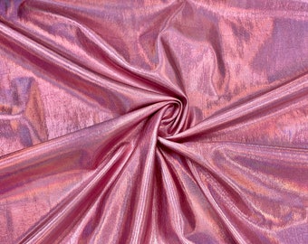 May include: A close-up shot of a shimmering, pink fabric with a metallic sheen. The fabric is gathered and folded, creating a swirling pattern in the center. The material has a textured surface and reflects light, creating highlights and shadows.