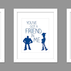 May include: Three white framed prints with blue silhouettes of characters from the movie Toy Story. The first print says "To Infinity and Beyond". The second print says "You've got a friend in me". The third print says "You're my favorite deputy".
