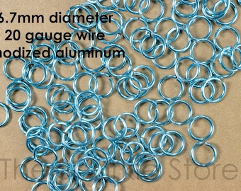 May include: A pile of 6.7 mm diameter jump rings made from 20 gauge anodized aluminum wire. The rings are a light blue color.