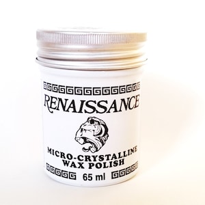 May include: A white jar with a silver lid labeled "Renaissance Micro-Crystalline Wax Polish" with a black and white illustration of a mythical creature. The jar contains 65 ml of polish.