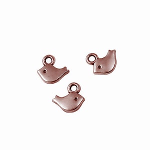 May include: Three small rose gold bird charms with a loop at the top for attaching to jewelry or other crafts.