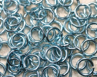 May include: A large pile of light blue metal jump rings. The rings are all the same size and are arranged in a random pattern.