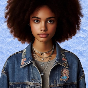 Könnte beinhalten: Eine Frau mit lockigem, dunkelbraunen Haar trägt eine blaue Jeansjacke mit Blumenstickerei. Sie trägt eine mehrlagige Halskette mit einem silbernen Anhänger. Ein kleiner Comic-Charakter mit braunen Haaren und einem blauen Hemd ist auf die Jacke gestickt.