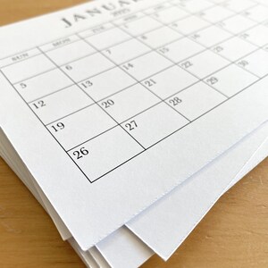 Puede incluir: Una pila de p&aacute;ginas de calendario en blanco para el mes de enero. El calendario est&aacute; impreso con el mes y el a&ntilde;o, y los d&iacute;as de la semana est&aacute;n etiquetados.