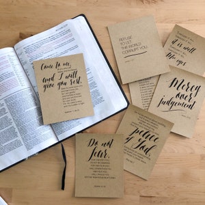 May include: A collection of eight inspirational quotes printed on brown paper cards. The quotes include "Come to me, all you who are weary and burdened, and I will give you rest." "Do not fear, for I am with you; do not be dismayed, for I am your God. I will strengthen you and help you; I will uphold you with my righteous right hand." "Refuse to let the world corrupt you." "Through it all, through it all, it is well, through it all, through it all, my eyes." "Love is patient, love is kind. It does not envy, it does not boast, it is not proud. It is not rude, it is not self-seeking, it is not easily angered, it keeps no record of wrongs. Love does not delight in evil but rejoices with the truth." "Do not be anxious about anything, but in every situation, by prayer and petition, present your requests to God. And the peace of God, which transcends all understanding, will guard your hearts and your minds in Christ Jesus." "Mercy over judgment."  "Isaiah 41:10", "Matthew 11:28-30", "James 1:27", "Psalm 46:6-7", "James 2:13".