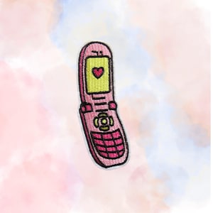 May include: Pink flip phone patch with a yellow screen displaying a red heart. The patch has a stitched design and a white border. The phone's buttons and details are in a darker pink.