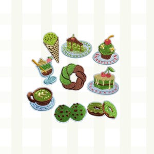 May include: A collection of embroidered patches featuring various desserts. Includes an ice cream cone, cake slices, a cupcake, a sundae, a donut, cookies, and a cup of matcha tea. The patches are in shades of green, brown, and white.