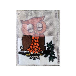 May include: A completed needlepoint project featuring a brown owl with orange and black accents perched on a branch with green leaves. The owl is set against a white background with a grid pattern.