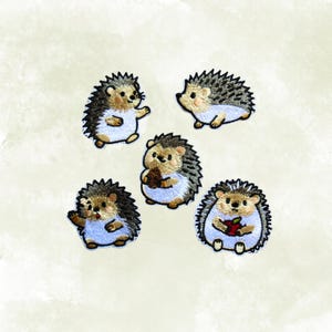 May include: Five embroidered hedgehog patches. Each patch features a hedgehog with a brown face, black quills, and a light blue belly. Some hedgehogs are holding objects, such as an apple or a nut.