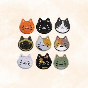 May include: Nine embroidered cat face patches in various colors, including orange, black, white, brown, and calico. Each patch features a smiling cat face with embroidered details. The patches are arranged in a three-by-three grid.