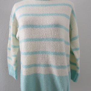 May include: A long-sleeve knit sweater featuring a ribbed mock neck collar. The garment displays a horizontal striped pattern in alternating bands of off-white and light turquoise blue, with a solid light turquoise blue hem at the bottom.