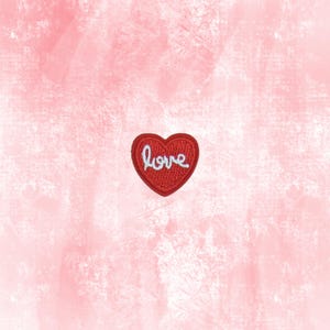 May include: A red heart-shaped patch with the word "love" embroidered in white cursive. The patch is centered on a textured pink background, creating a romantic and decorative element.
