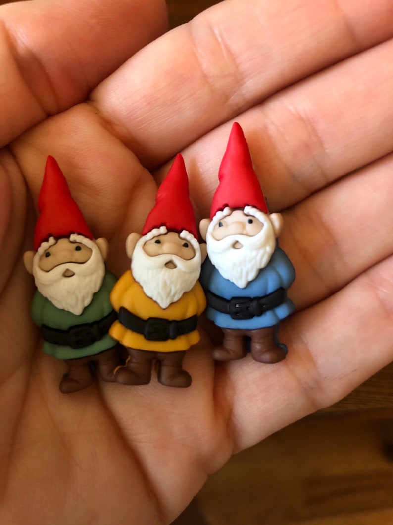 May include: Three small gnome figurines with red hats, white beards, and different colored outfits: green, yellow, and blue.
