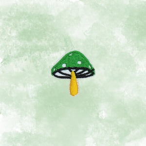 May include: Embroidered patch featuring a green mushroom with white polka dots on the cap, a yellow stem, and a black and white border. The patch is set against a light green watercolor background, creating a whimsical and nature-inspired design.