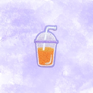 May include: Embroidered patch featuring a refreshing orange drink in a clear plastic cup with a lid and straw. The patch has a purple border and is set against a watercolor-style purple background.