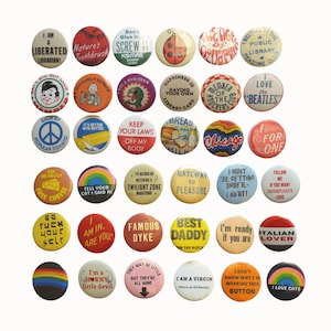May include: A collection of thirty-five circular pin-back buttons arranged in six rows. Each button features unique colorful graphics, illustrations, and various slogans or phrases printed in different fonts, colors, and styles on a white background.