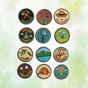 May include: Twelve circular embroidered patches featuring outdoor themes. Designs include a pickaxe with "TRAILBLAZER", animal tracks, a hat with "LITTLE EXPLORER", a climber with "MOUNTAIN CLIMBING", a magnifying glass, a telescope with "STARGAZER", a hiker with "HIKING", a mountain landscape, a slingshot with "EXPERT TROUBLEMAKER", marshmallows with "PICNIC MASTER", a tent, and a hot air balloon with "ADVENTURE SEEKER".