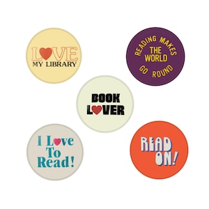 May include: A collection of five round buttons with text related to reading. The buttons are in various colors, including yellow, purple, and orange. Text includes "Love My Library," "Reading Makes the World Go Round," "Book Lover," "I Love To Read!," and "Read On!"