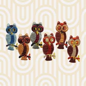 May include: Set of seven embroidered iron-on owl patches in various colors, including blue, red, orange, and brown. The owls have different patterns and designs.